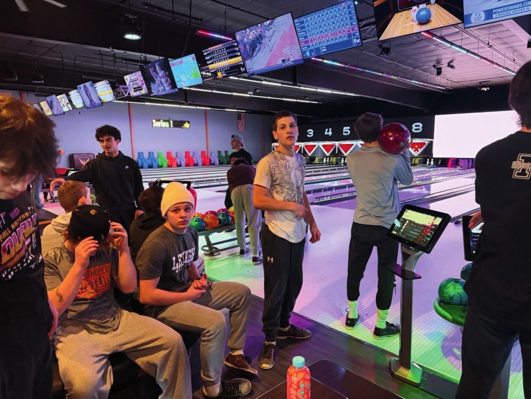 Teammates gather at a bowling lane during a team outing