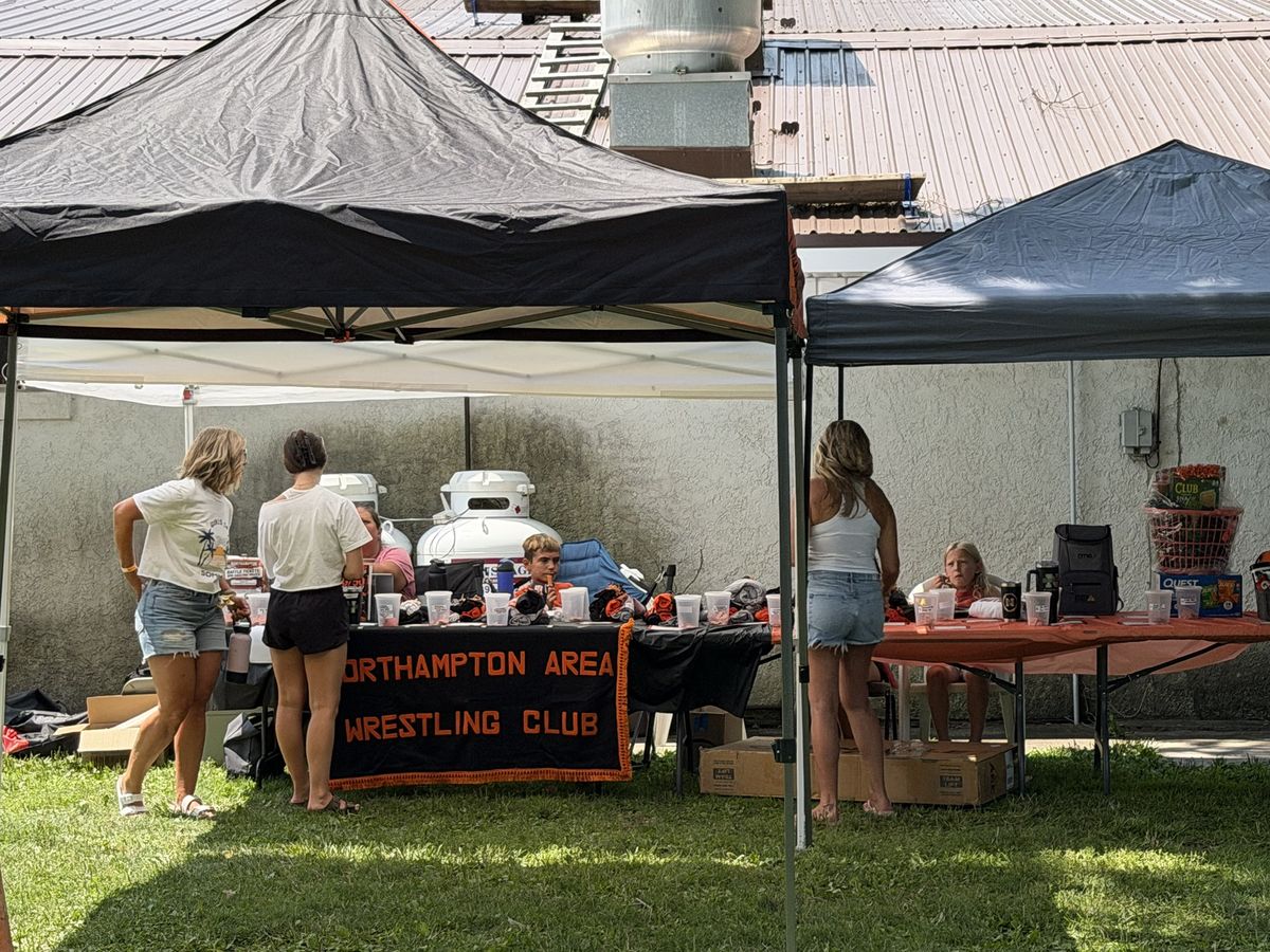 Volunteers work the Northampton Area Wrestling Club table under black canopies
