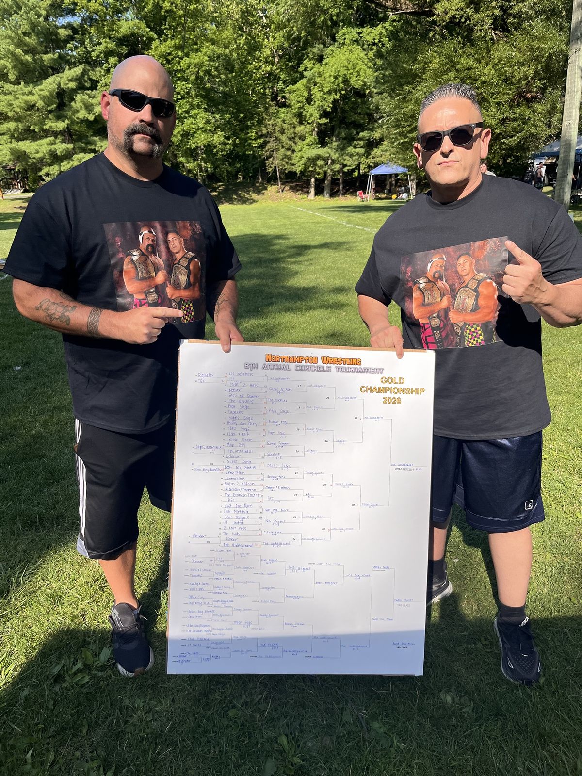 Two players in matching shirts hold the completed Gold Championship bracket