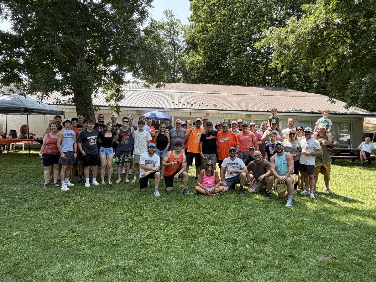 A large group of players, families and Northampton wrestlers poses on the grass in front of the pavilion
