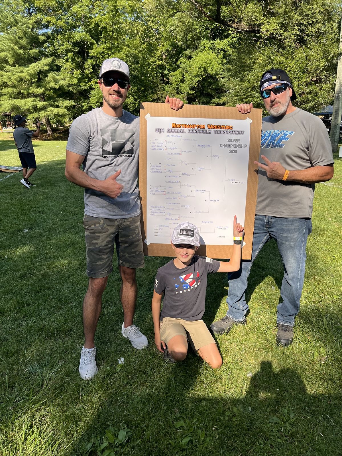 Two players and a young fan pose with the completed Silver Championship bracket