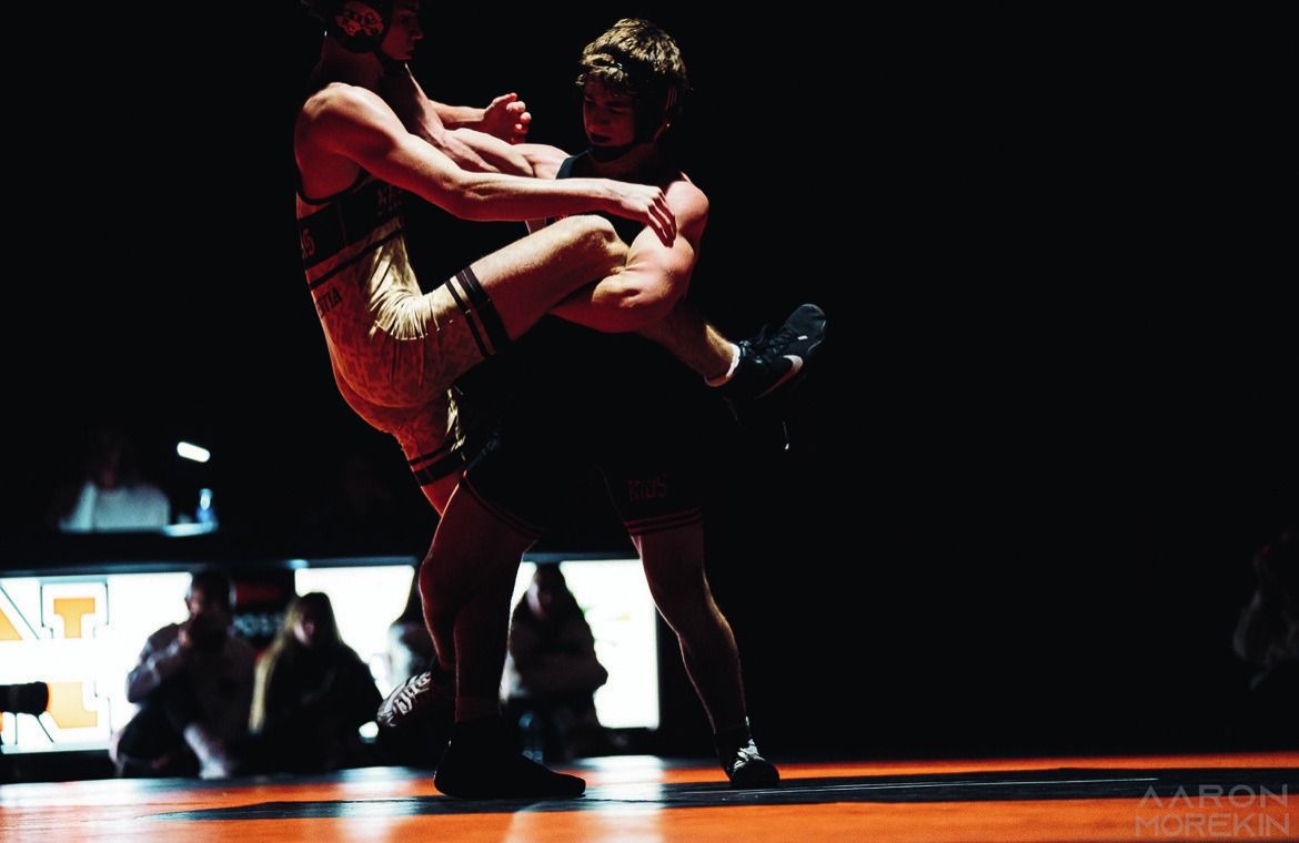 A Northampton wrestler drives into his opponent under dramatic lighting