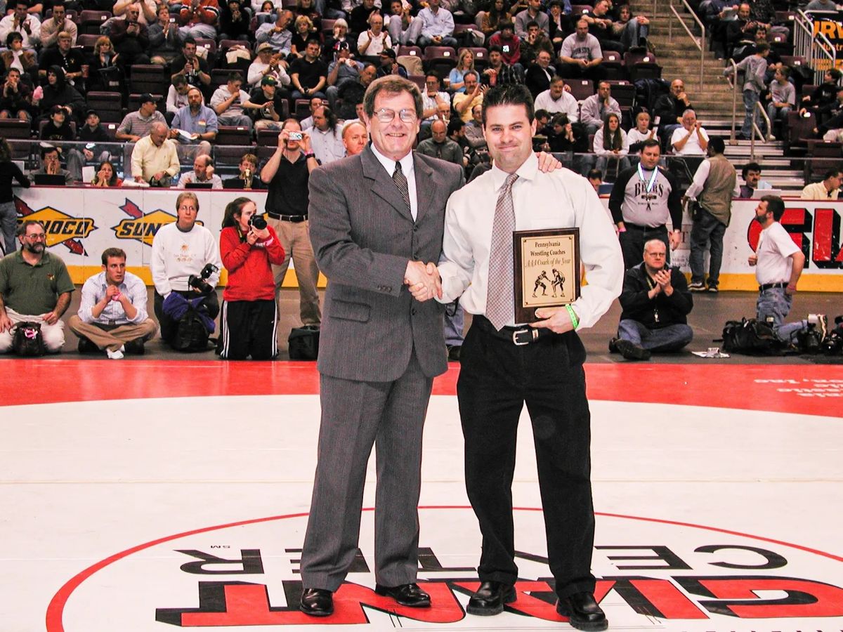 Coach Terry Daubert holds his Pennsylvania Wrestling Coaches AAA Coach of the Year plaque on the mat at the Giant Center