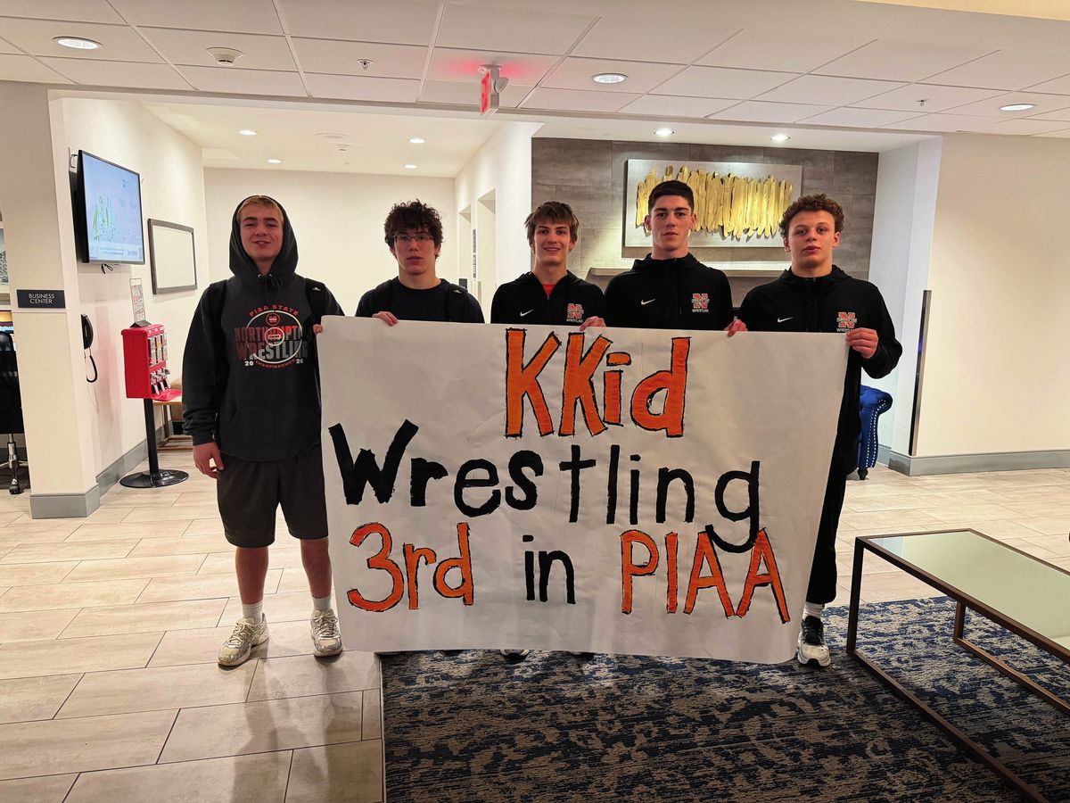 Northampton wrestlers hold a hand-painted sign that reads KKid Wrestling 3rd in PIAA