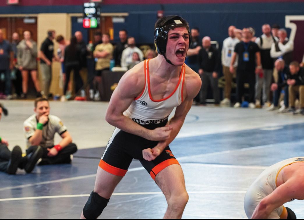 A Northampton wrestler roars with his fists clenched after a win
