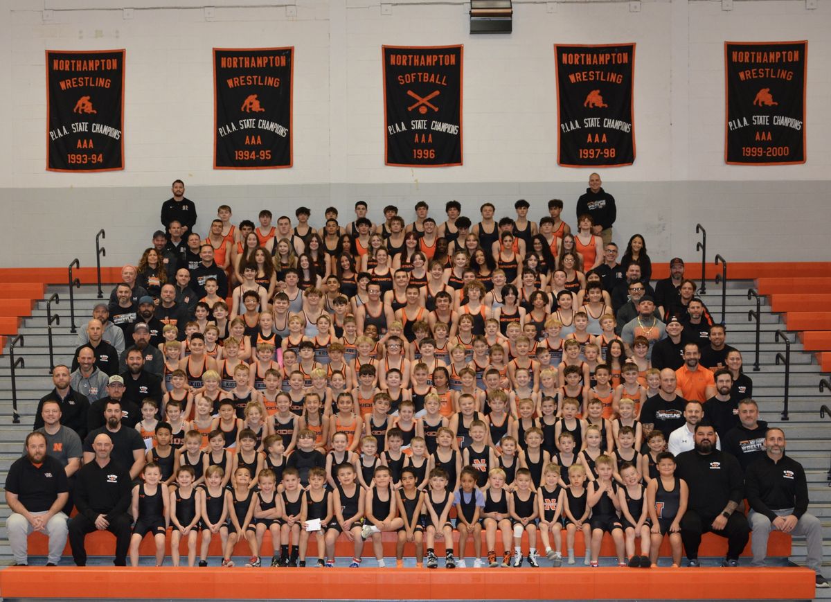 The whole Northampton wrestling program, from the youngest youth wrestlers to the varsity, with coaches, in the gym bleachers below the state championship banners