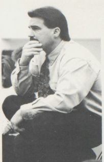Coach Don Rohn watches a match from the corner, hand at his chin