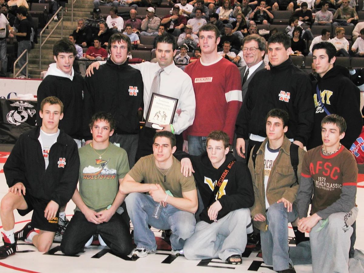 Northampton wrestlers gather around Coach Terry Daubert and his Coach of the Year plaque on the Giant Center mat
