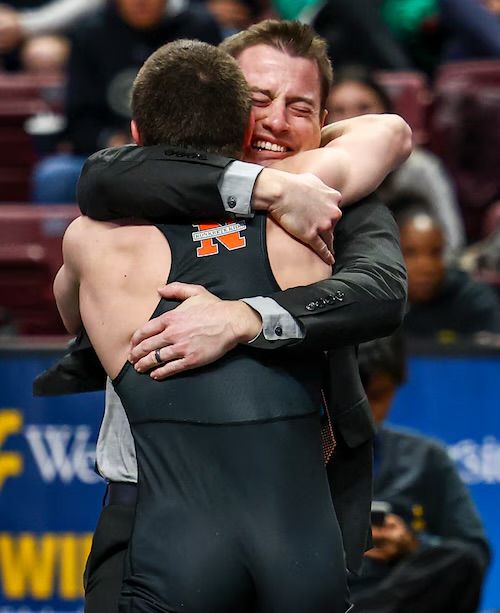 Coach Joe Provini hugs Trey Wagner, eyes shut and smiling, after Wagner's 2024 state championship