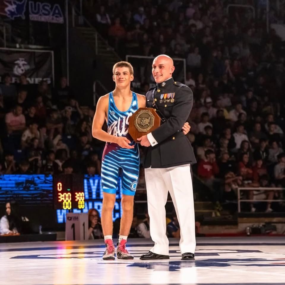 Brayden Wenrich, in a Team Pennsylvania singlet, holds his national champion plaque on the mat at Fargo