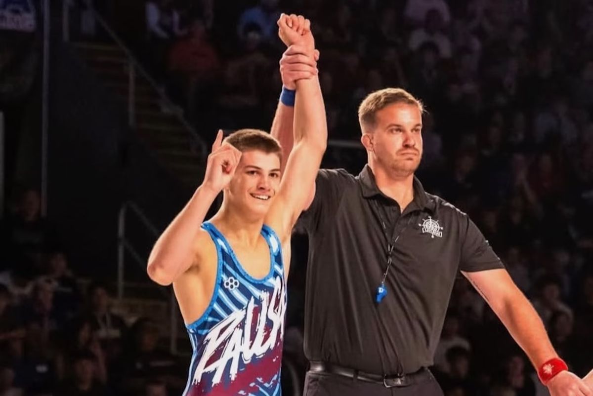 The referee raises Brayden Wenrich's hand as he points a finger skyward after the Fargo final