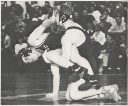 Whitey Chlebove controls an opponent from behind in front of a packed crowd