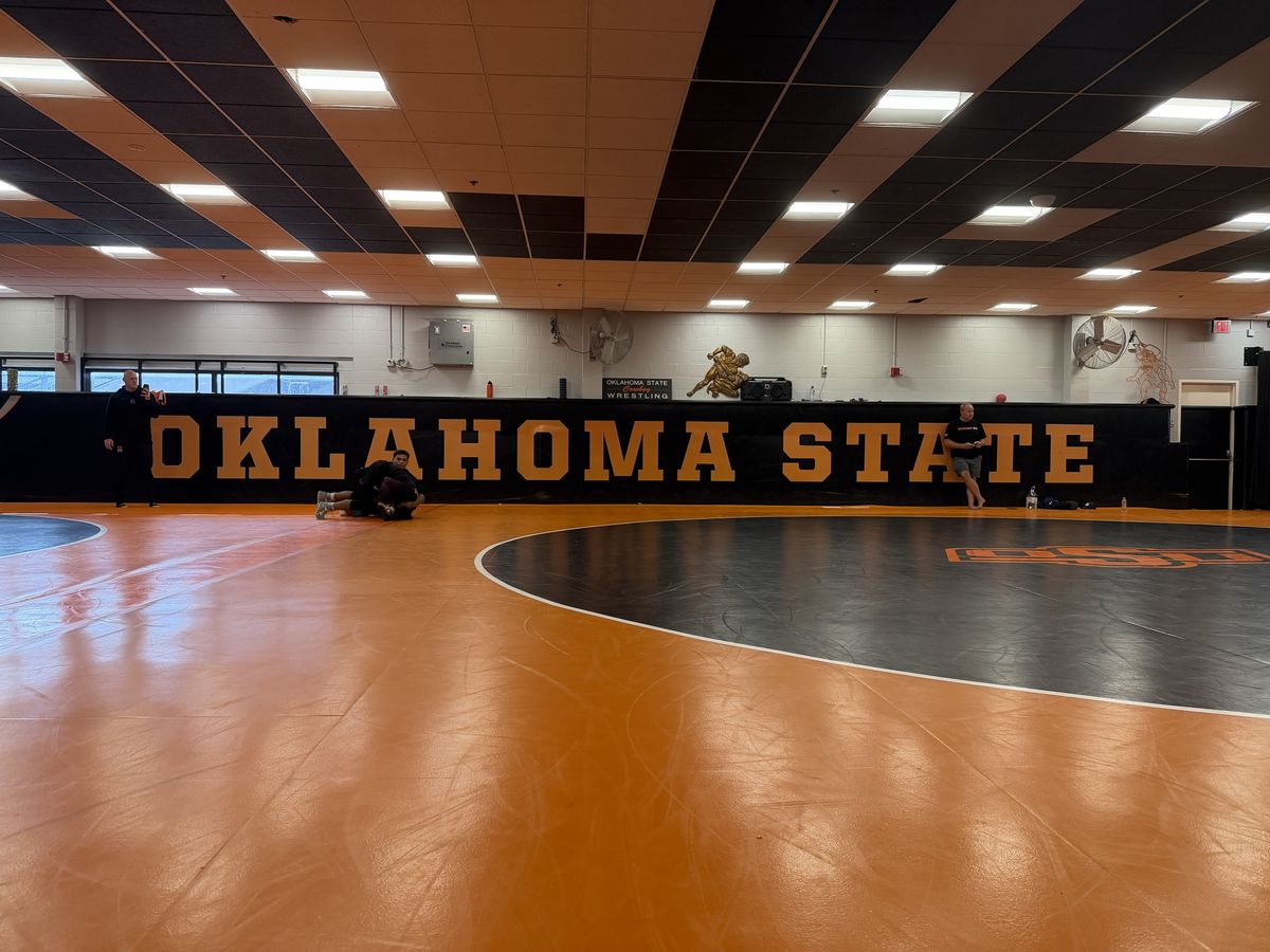 The Oklahoma State wrestling room, with orange and black mats and OKLAHOMA STATE on the wall